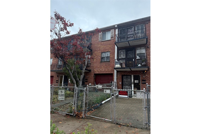 Traditional-style home with a gate, brick siding, a fenced front yard, and a balcony