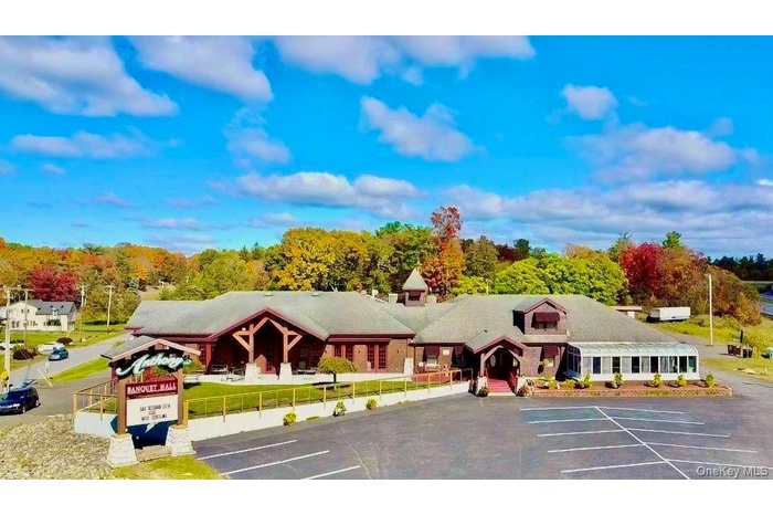 View of property featuring uncovered parking and a wooded view