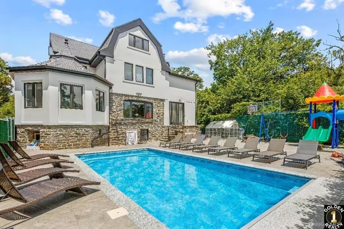 Back of house with a patio, stucco siding, stone siding, and an outdoor pool