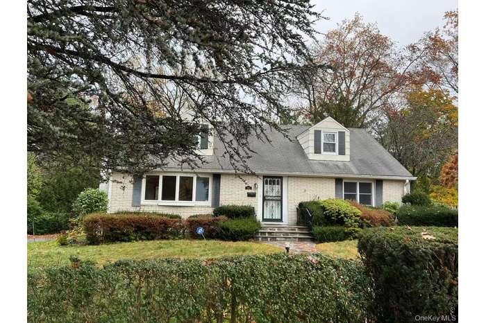 New england style home featuring brick siding and roof with shingles