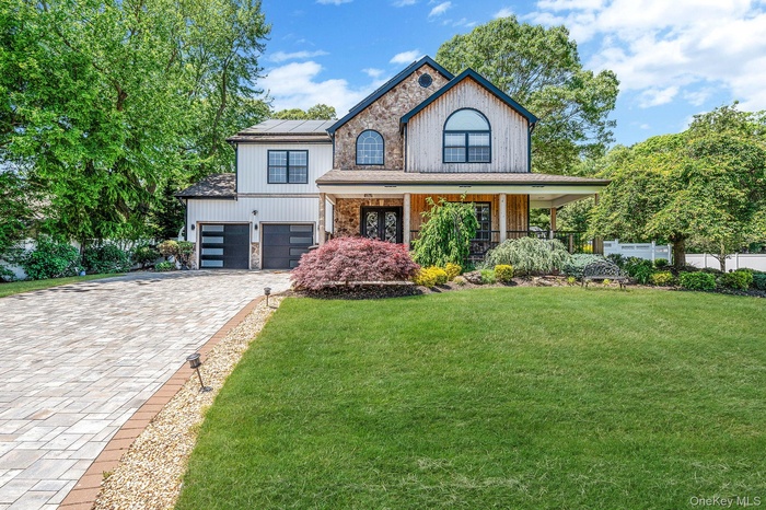 View of front of home with covered porch, decorative driveway, roof mounted solar panels, and a garage