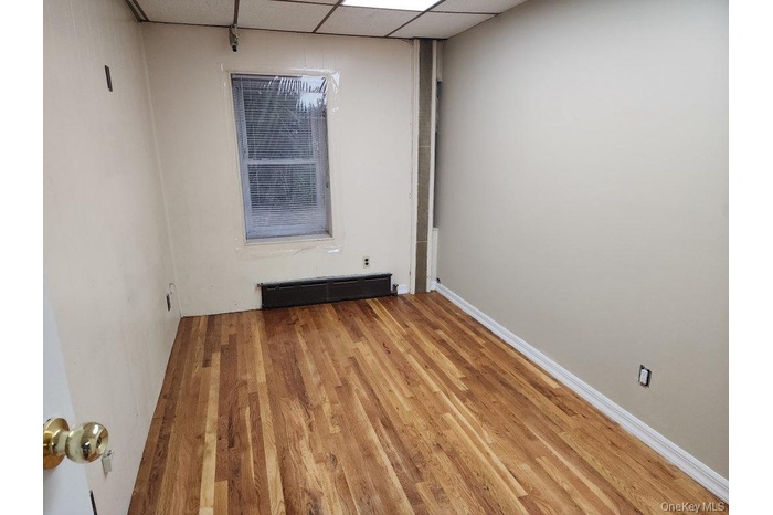 Unfurnished room featuring a paneled ceiling, wood finished floors, and baseboard heating