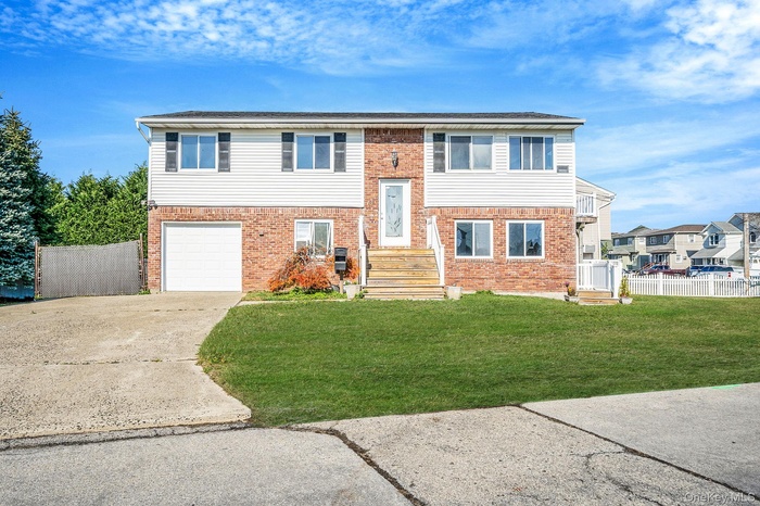 Raised ranch featuring driveway, brick siding, and a garage