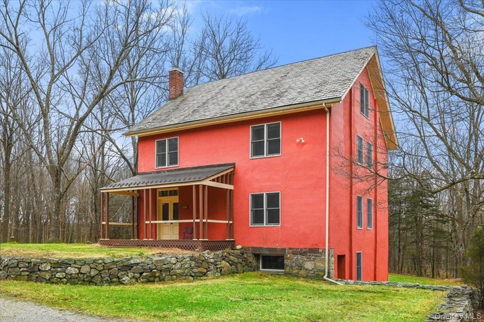 View of front facade with a front yard, a chimney, stucco siding, and a porch