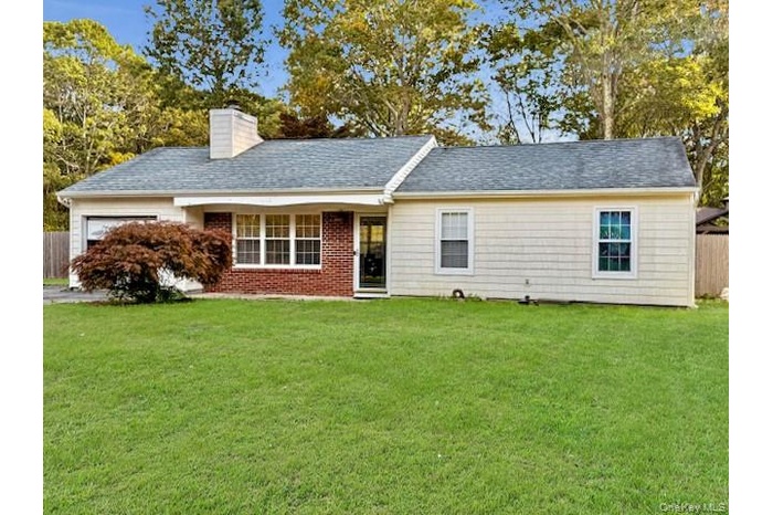 Single story home with a chimney, an attached garage, and a shingled roof