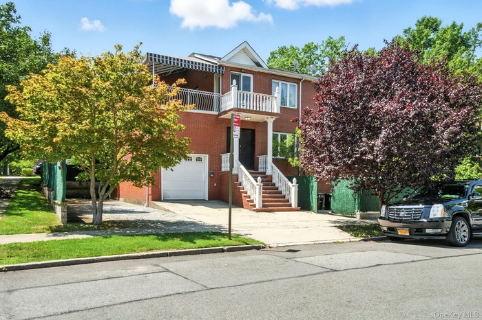 View of front of home with a balcony, driveway, brick siding, and a garage