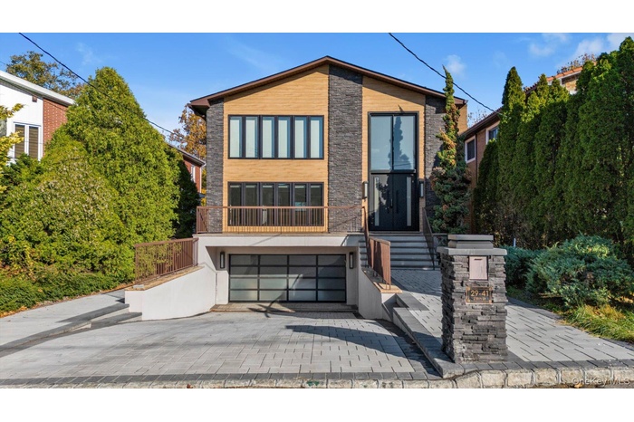Modern home with decorative driveway, an attached garage, and stone siding