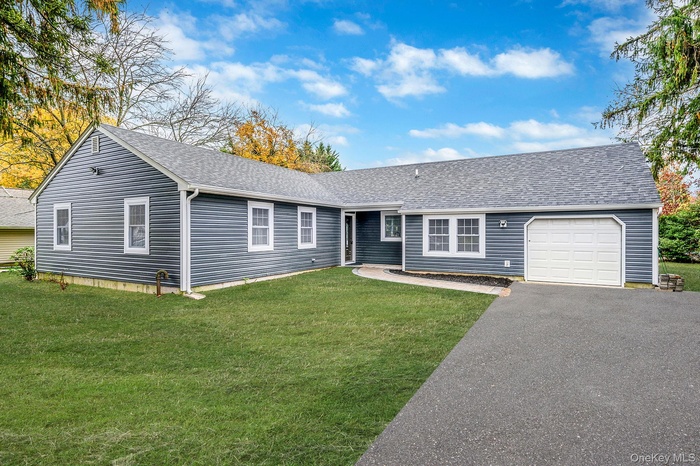 Single story home featuring roof with shingles, asphalt driveway, a front yard, and a garage