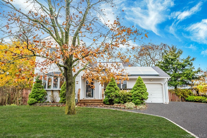 View of front of house with driveway, a garage, and roof mounted solar panels
