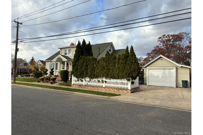 View of front of property with a fenced front yard, concrete driveway, a chimney, and a detached garage