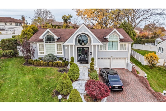 Traditional-style home with a shingled roof, decorative driveway, stucco siding, an attached garage, and french doors