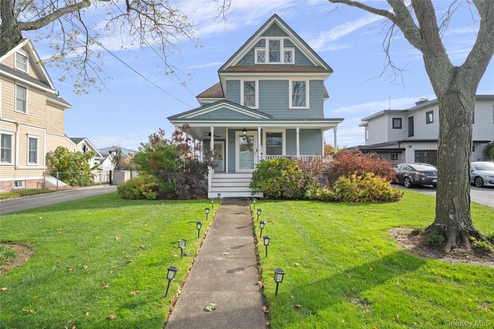 View of front of house featuring a porch, a front yard, and roof with shingles