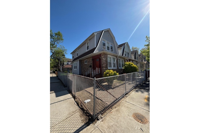 View of front of property with a residential view, a fenced front yard, a gambrel roof, and stone siding