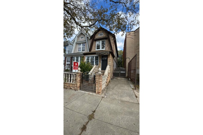 View of front facade with a gambrel roof and a gate
