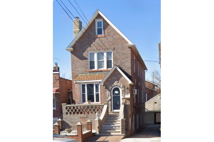 View of front of home featuring brick siding, a chimney, and an outdoor structure