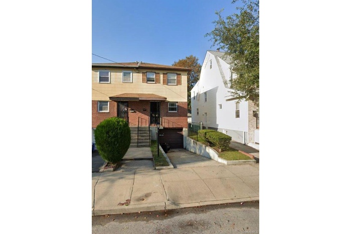 Traditional home featuring driveway, brick siding, and an attached garage