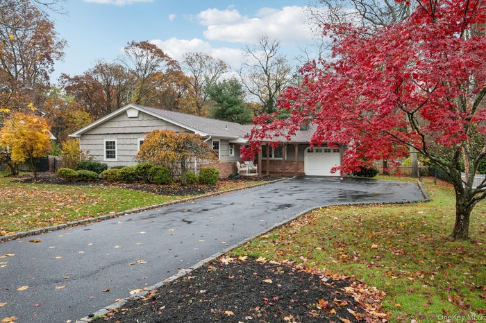 View of front of house featuring asphalt driveway, an attached garage, and brick siding