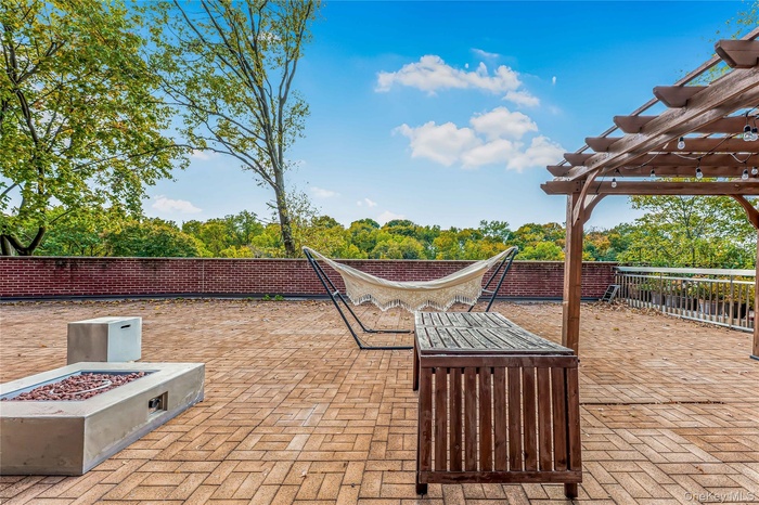 Fenced backyard with a pergola, an outdoor fire pit, and view of wooded area