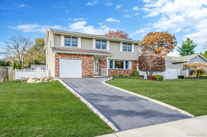 View of front facade with asphalt driveway, brick siding, and an attached garage