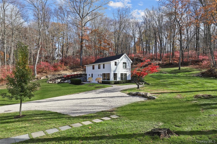 View of front facade featuring a front yard, board and batten siding, and driveway