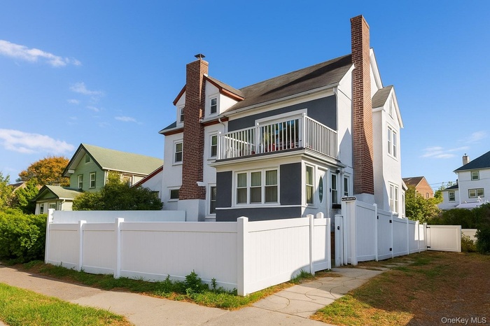 View of front facade with a chimney, a balcony, and stucco siding