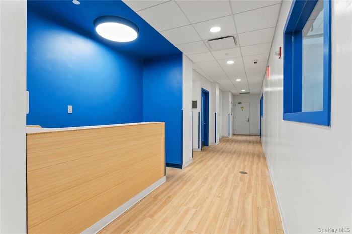 Hallway with a paneled ceiling, wood finished floors, and recessed lighting