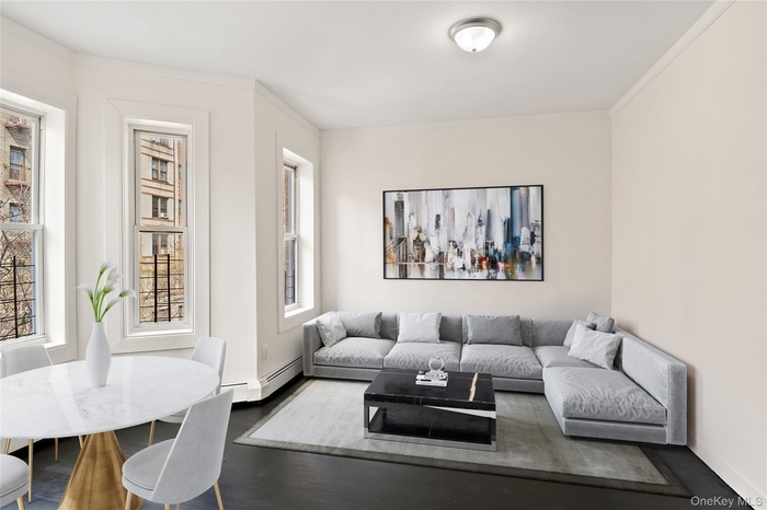 Living room featuring baseboard heating, crown molding, and wood finished floors