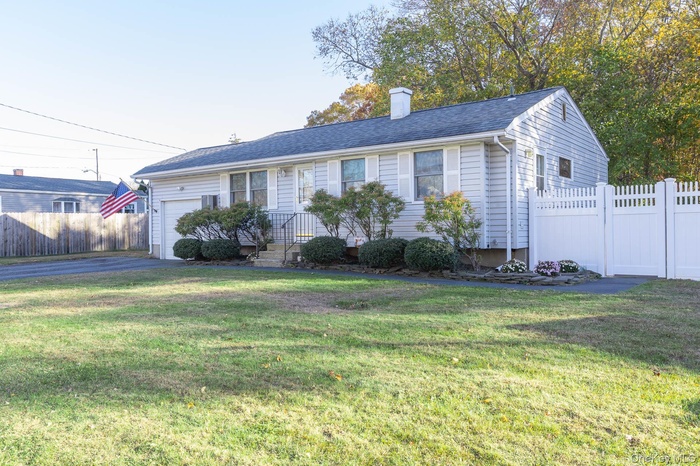 View of front of property with a chimney, driveway, an attached garage, and a shingled roof