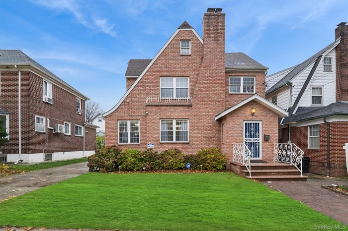 View of front of home featuring a chimney, a front lawn, brick siding, and a shingled roof