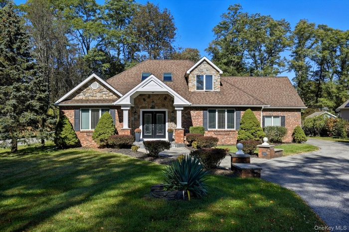 Craftsman house featuring a front yard, brick siding, stone siding, and a shingled roof