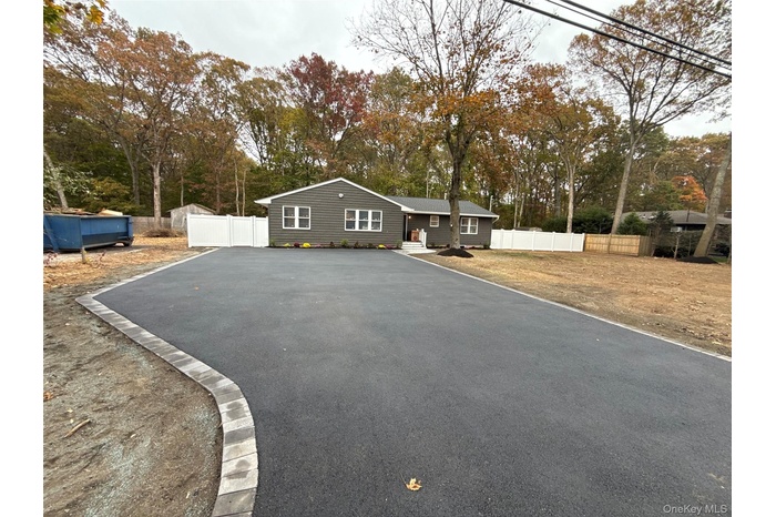 View of front of home with asphalt driveway and view of scattered trees