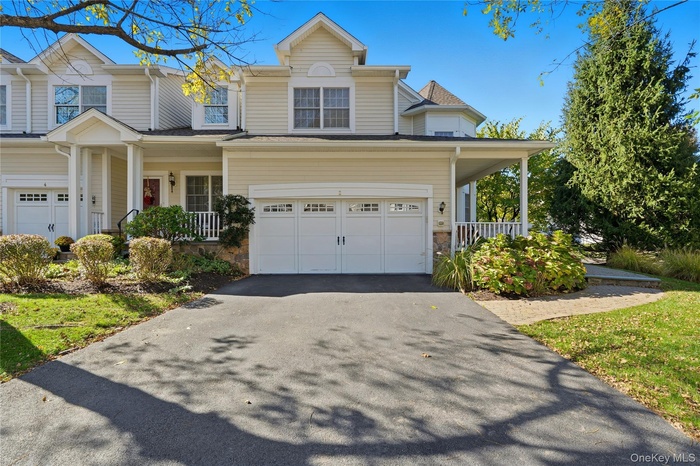 Traditional home with covered porch, driveway, a garage, and stone siding