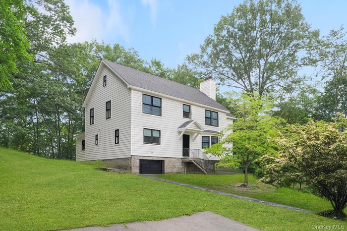 View of front facade featuring a chimney, an attached garage, and a front yard
