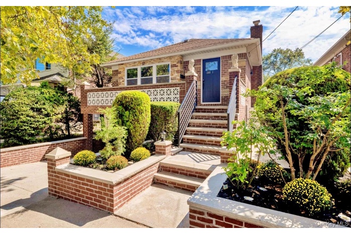 View of front facade featuring a chimney, brick siding, and a patio area
