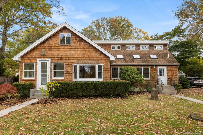 View of front of home with a front lawn and a shingled roof