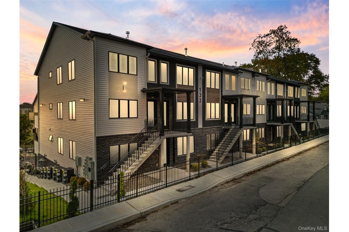 Property at dusk with a fenced front yard and stairs