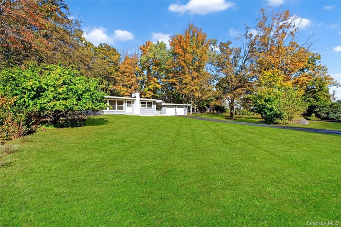 View of grassy yard with a garage and view of wooded area