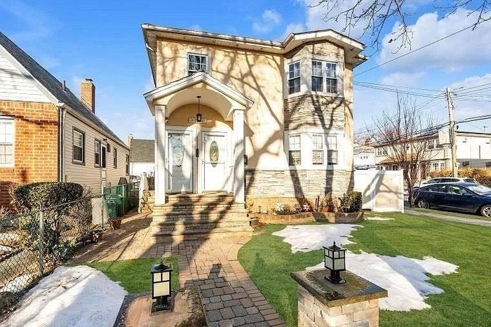 View of front of home with stucco siding, fence, stone siding, and a front yard