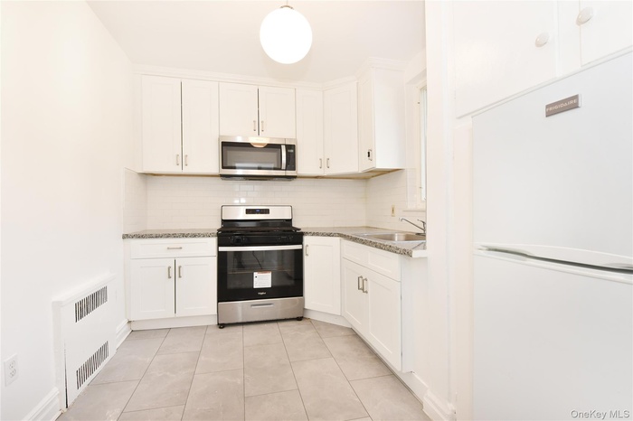 Kitchen featuring stainless steel appliances, tasteful backsplash, and white cabinets