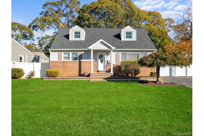 Cape cod home with brick siding, a chimney, a shingled roof, and a garage