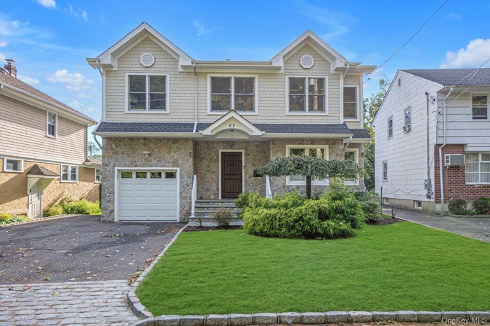 View of front of house with stone siding, asphalt driveway, a front lawn, an attached garage, and roof with shingles
