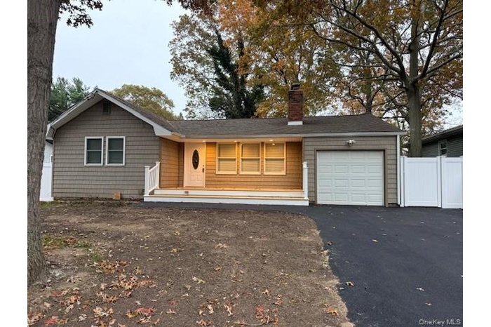 Ranch-style house with asphalt driveway, a garage, a chimney, and a porch