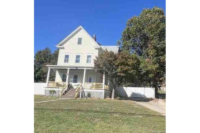 View of front of home with covered porch and a front yard