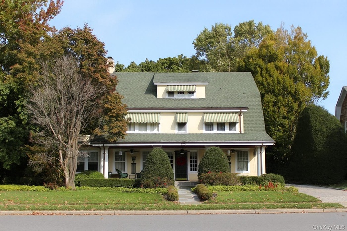 View of front of house featuring a porch, a front yard, and roof with shingles
