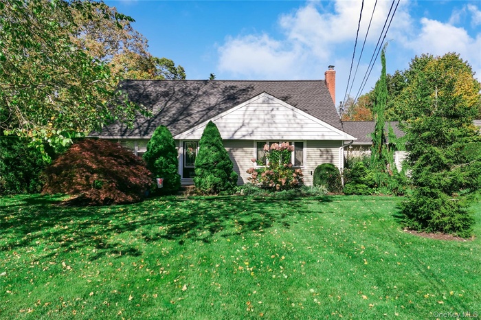 View of front facade featuring a front yard, a chimney, and roof with shingles