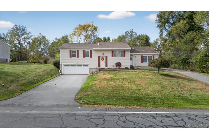 Bi-level home featuring asphalt driveway, a front lawn, and an attached garage