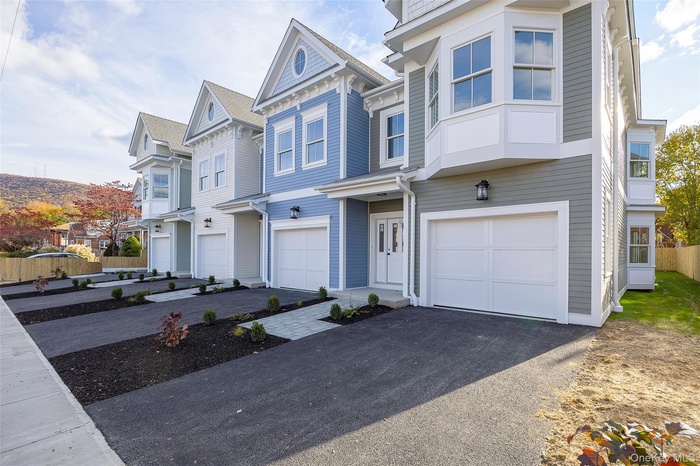 View of front of house with a residential view, an attached garage, and driveway