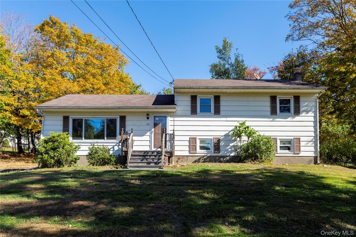 Tri-level home featuring a front lawn and a chimney