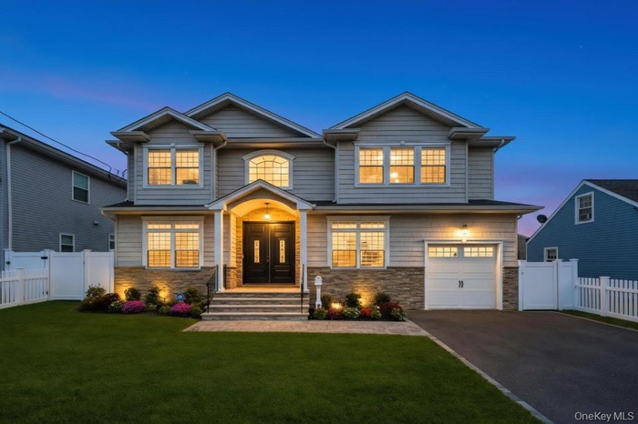 View of front of property with driveway, stone siding, and a garage