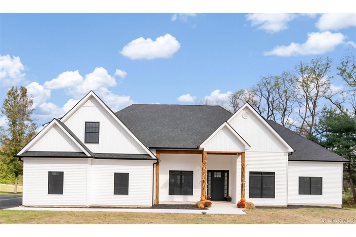 View of front of house featuring a shingled roof, a porch, a front lawn, and board and batten siding